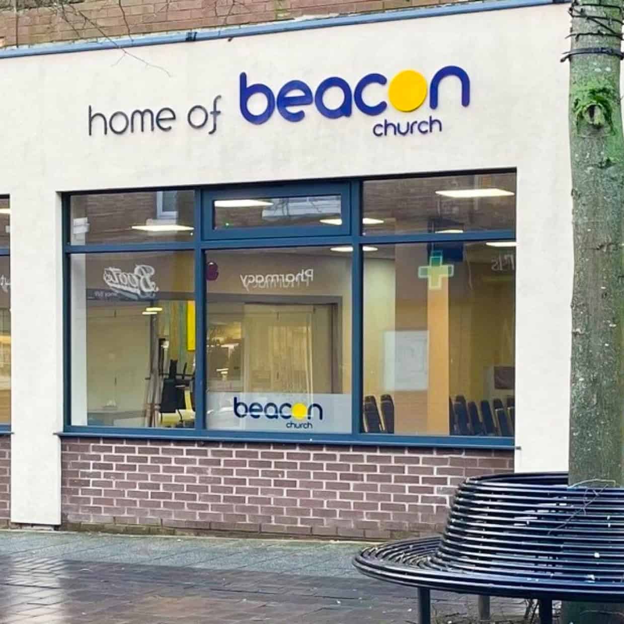 Exterior of Beacon Church in Whitchurch with signage and windows showing the interior.