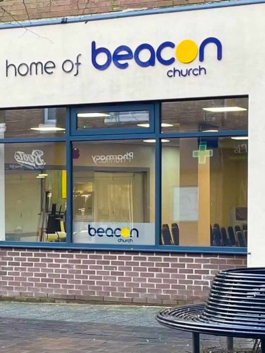 Exterior of Beacon Church in Whitchurch with signage and windows showing the interior.