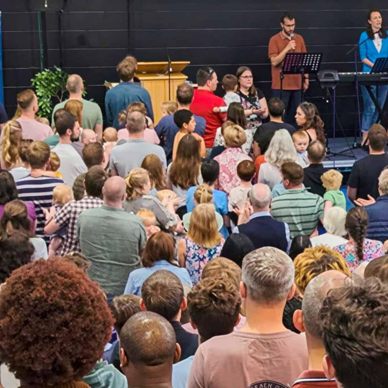Large congregation gathered inside a church during a worship service with musicians leading at the front.