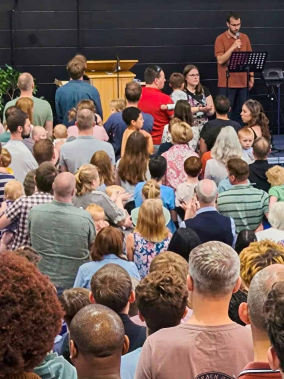 Large congregation gathered inside a church during a worship service with musicians leading at the front.