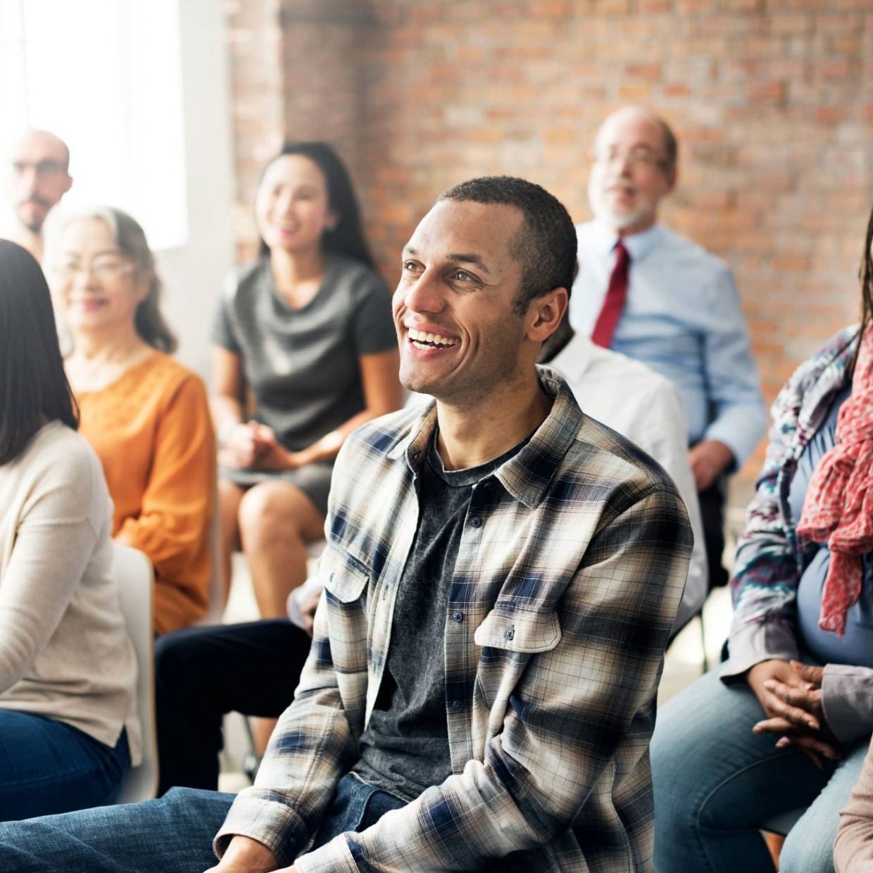 Group of people sitting and smiling in a church setting, listening and engaging together during a service or talk.