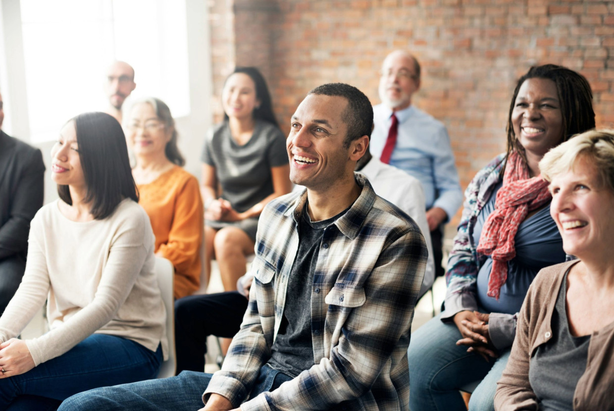 Group of people sitting and smiling in a church setting, listening and engaging together during a service or talk.