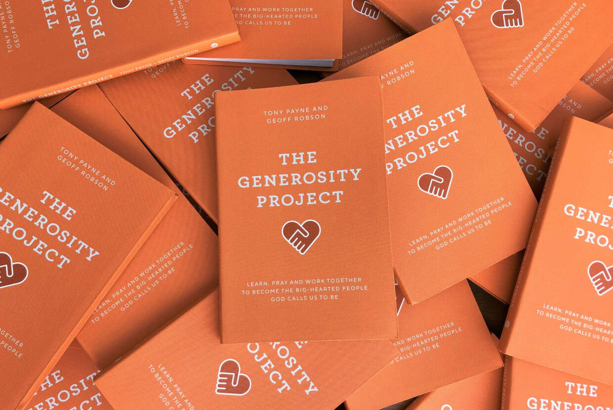 Multiple copies of The Generosity Project book with orange covers arranged in a stack.