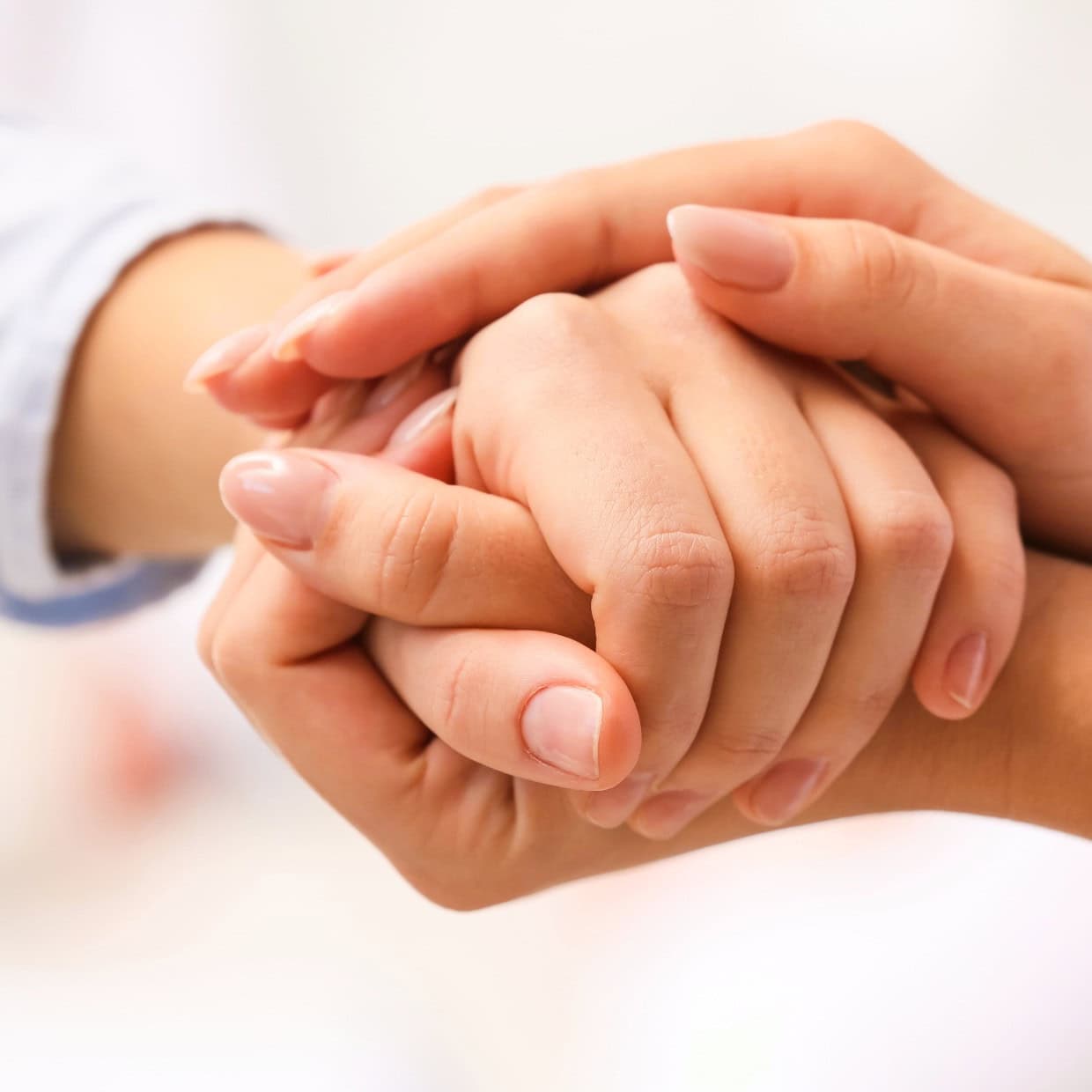 Close up of one person gently holding another person’s hands in a caring and supportive gesture.