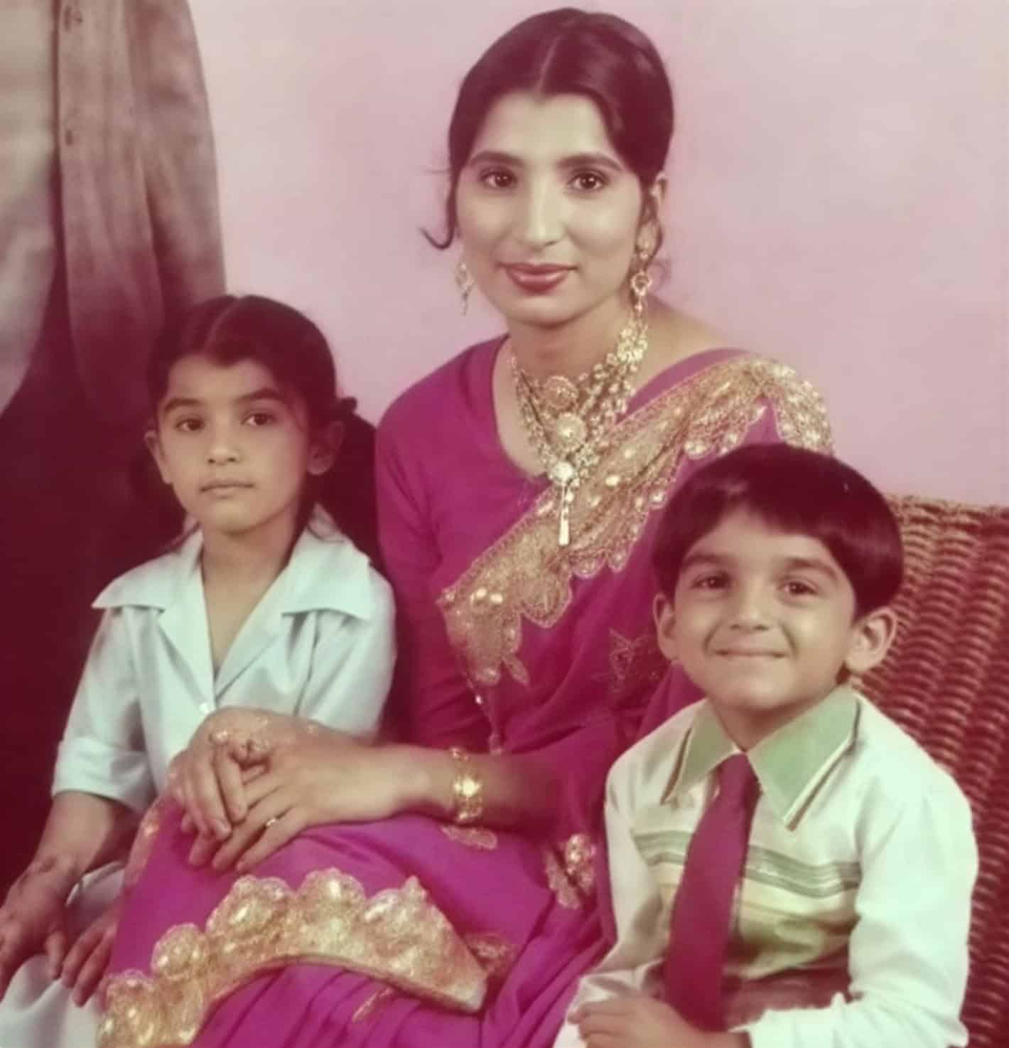 Childhood portrait of Pod as a young boy sitting with his family, including a woman in traditional dress and another child, posed indoors.
