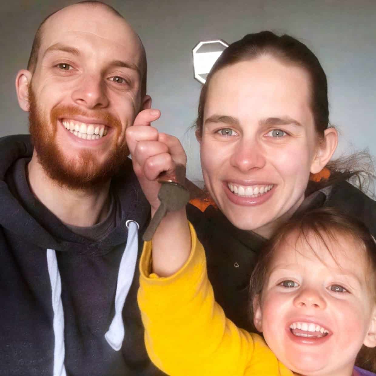The Tuck family smiling together with a child holding up a key indoors.