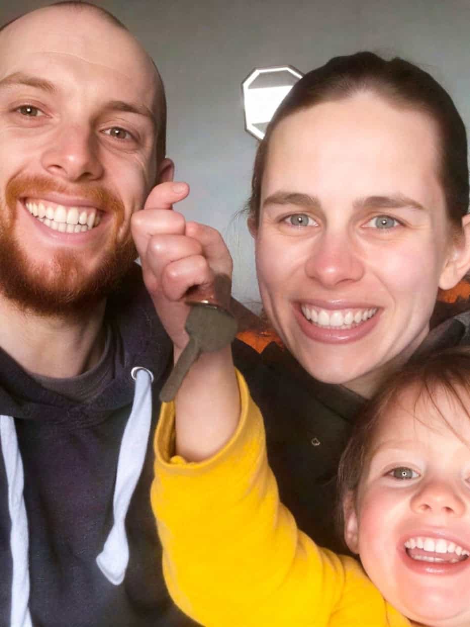 The Tuck family smiling together with a child holding up a key indoors.